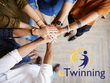 Man sieht wie die Hände von fünf Personen übereinander zusammengelegt um Einigkeit zu signalisieren. Rechts darunter ist das eTwinning-Logo