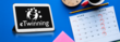 Auf einem blauen Hintergrund liegt ein Tablet mit eTwinning-Logo auf dem Bildschirm. Daneben eine Kalender mit angestrichenen Donnerstagen sowie ein volle Kaffeetasse und ein Bleistift