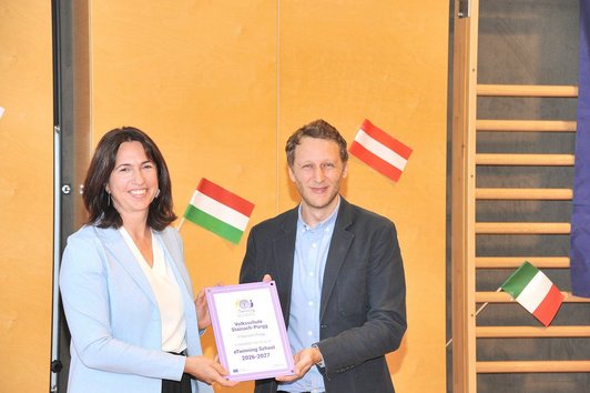 Schulleiterin Michaela Krondorfer und eTwinning-Österreich Mitarbeiter Frederic Bayersburg halten das Schulsiegel