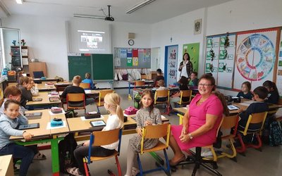 Foto aus dem Klassenzimmer der Gewinnerklasse. Lehrerin Roswitha Zeger sitzt gemeinsam mit den Kindern in der Klasse.