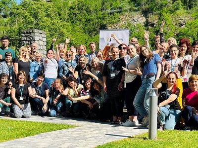 Foto aller Teilnehmerinnen und Teilnehmer des eTwinning-Donauraumseminars 2023. In etwas 50 Teilnehmer/innen stehen mit freudigem Blick und teils gehobenen Armen vor einem grünen Weinhügel.