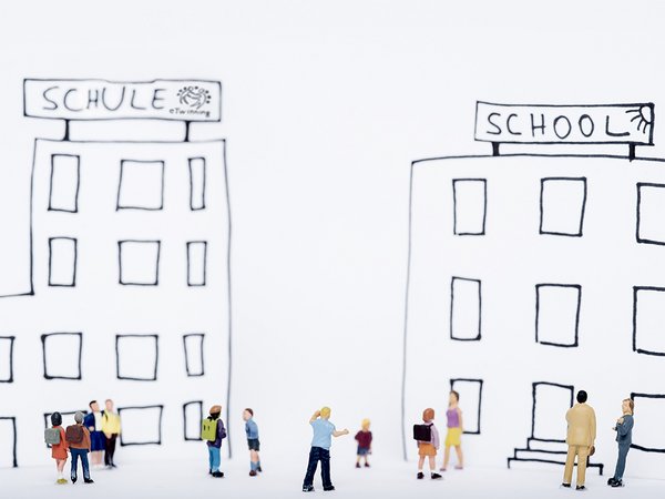 Spielzeugfiguren stehen vor gezeichnetem Schulgebäude