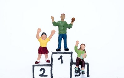 Drei Spielzeugfiguren stehen auf einem gebastelten Podest.