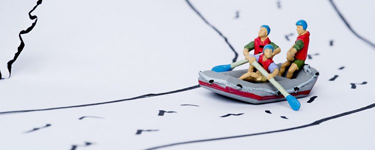 Drei Spielzeigfiguren sitzen in einem Spielzeugboot und fahren auf einem gezeichneten Fluss