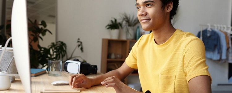 Jugendlicher in gelben T-Shirt vor einem Computer