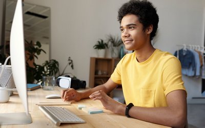 Jugendlicher in gelben T-Shirt vor einem Computer